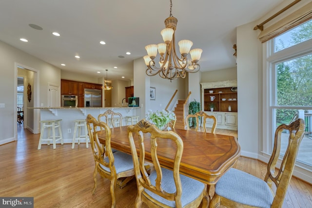 dining space featuring light wood-style flooring, a notable chandelier, stairs, and recessed lighting