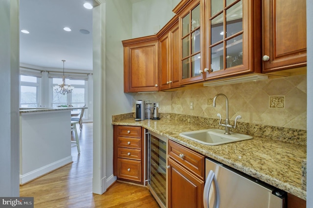kitchen featuring refrigerator, backsplash, light wood finished floors, beverage cooler, and a sink