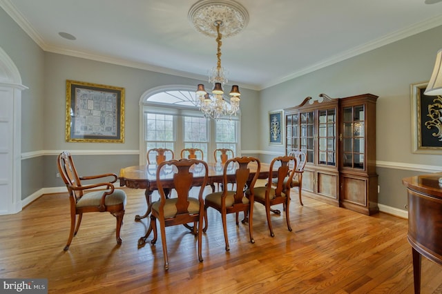 dining area with crown molding, baseboards, a chandelier, and light wood-style floors