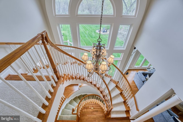 stairway featuring a notable chandelier, a high ceiling, and wood finished floors