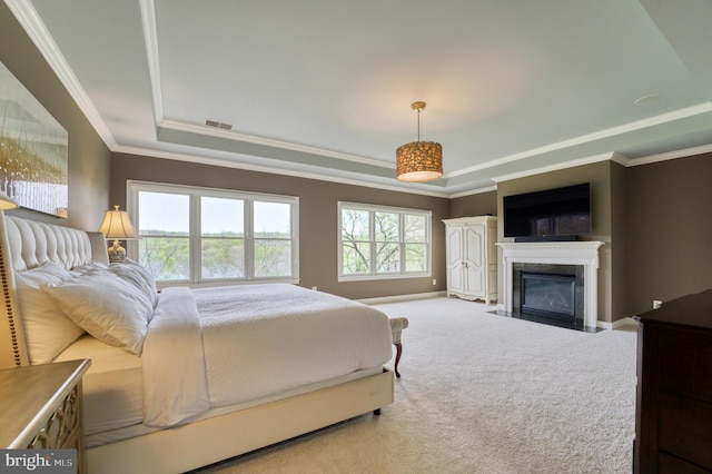 carpeted bedroom with a fireplace with flush hearth, visible vents, ornamental molding, and a raised ceiling