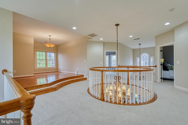 corridor with visible vents, carpet flooring, baseboards, and an upstairs landing