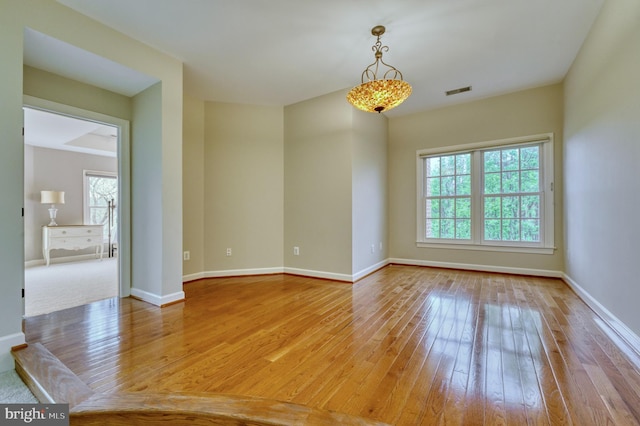 spare room featuring hardwood / wood-style floors, baseboards, and visible vents