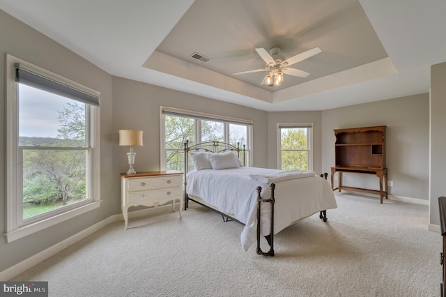 carpeted bedroom featuring ceiling fan, visible vents, baseboards, and a raised ceiling