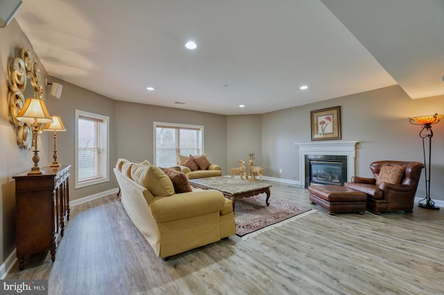 living room with a premium fireplace, wood finished floors, baseboards, and recessed lighting