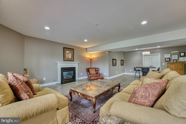 living room featuring a glass covered fireplace, recessed lighting, light wood-style floors, and baseboards