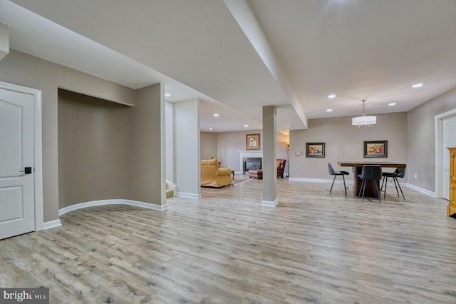 living area with wood finished floors, baseboards, a glass covered fireplace, and recessed lighting