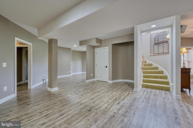 finished below grade area with baseboards, light wood-type flooring, and stairs
