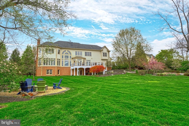 back of house featuring a yard, a deck, and brick siding