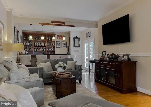 living area featuring built in features, bar area, crown molding, and light wood-style flooring