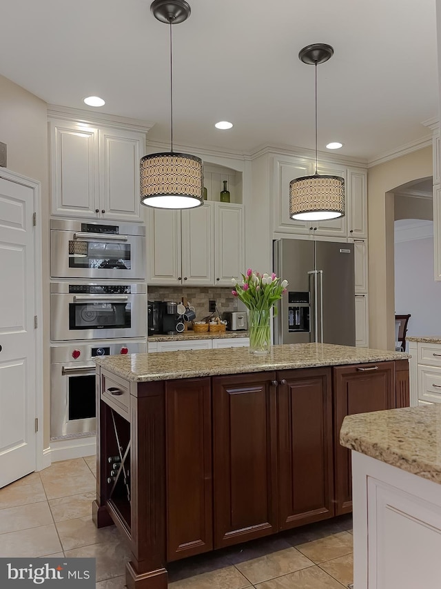 kitchen featuring stainless steel appliances, white cabinets, decorative light fixtures, and tasteful backsplash