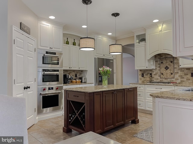 kitchen with tasteful backsplash, white cabinetry, stainless steel appliances, and decorative light fixtures