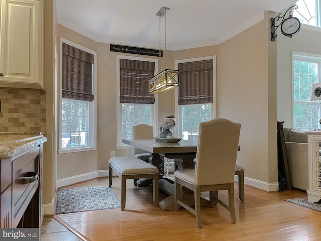 dining space featuring light wood-type flooring, a wealth of natural light, and crown molding