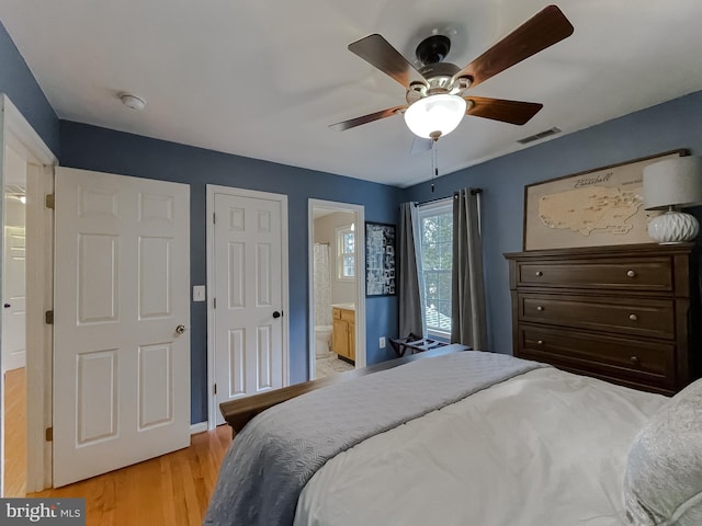 bedroom with light wood finished floors, ensuite bath, visible vents, and a ceiling fan