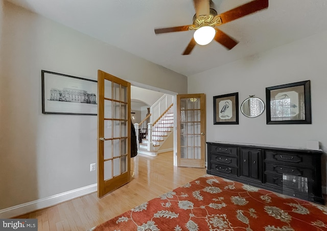 unfurnished room with baseboards, arched walkways, wood finished floors, stairs, and french doors