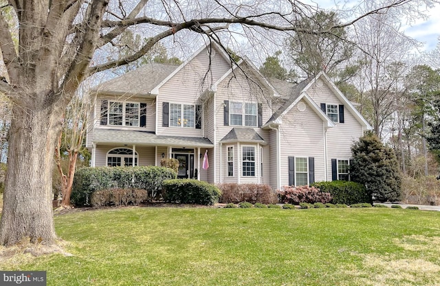 view of front facade with a front yard and roof with shingles