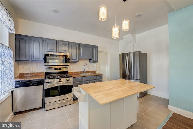 kitchen featuring light tile patterned floors, gray cabinets, stainless steel appliances, and a sink