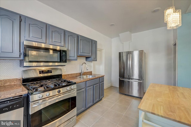 kitchen featuring light tile patterned floors, tasteful backsplash, gray cabinetry, appliances with stainless steel finishes, and a sink