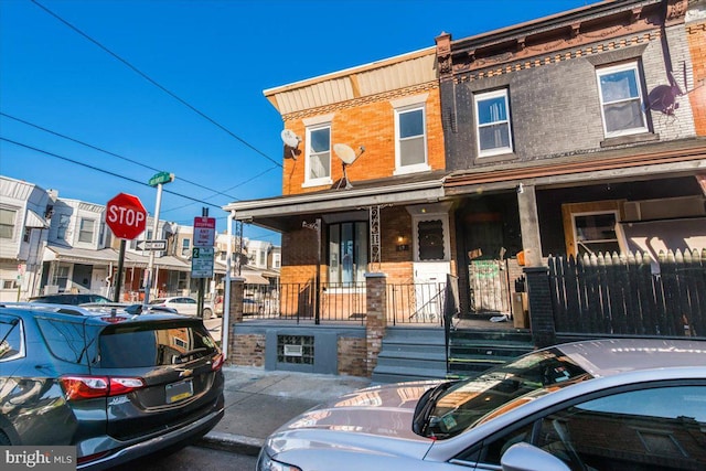 townhome / multi-family property featuring covered porch and brick siding