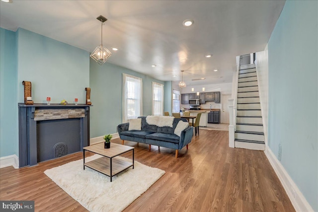 living room with recessed lighting, wood finished floors, a chandelier, baseboards, and stairs