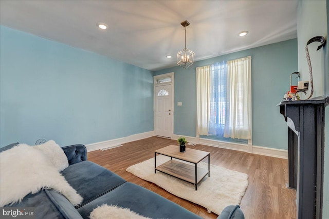 living room with a chandelier, a fireplace, wood finished floors, and baseboards