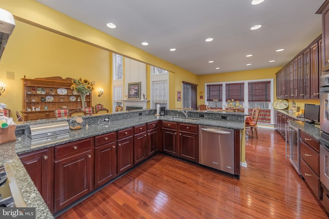 kitchen featuring dark wood-style flooring, recessed lighting, a sink, dark brown cabinets, and dishwasher