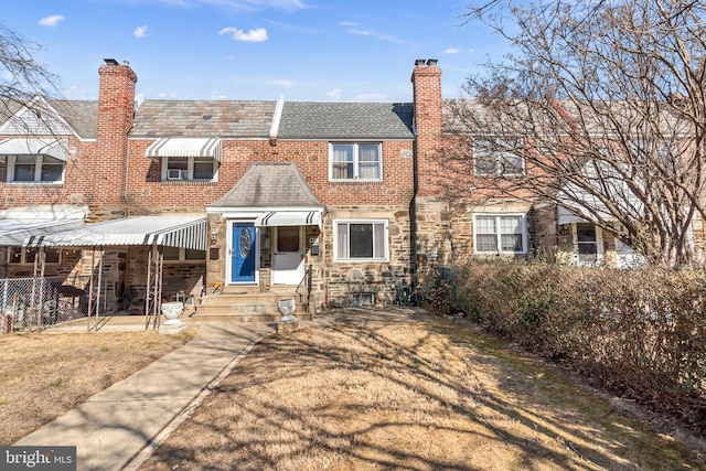 townhome / multi-family property featuring stone siding, a chimney, and a front yard