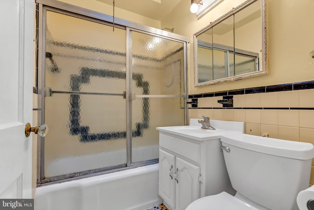 full bathroom featuring enclosed tub / shower combo, toilet, a wainscoted wall, vanity, and tile walls