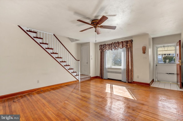 foyer entrance with stairway, radiator heating unit, ceiling fan, baseboards, and hardwood / wood-style flooring