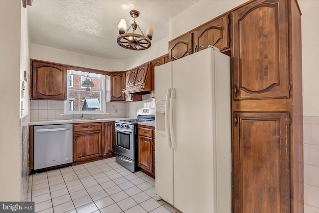 kitchen featuring a textured ceiling, decorative backsplash, stainless steel appliances, and light countertops