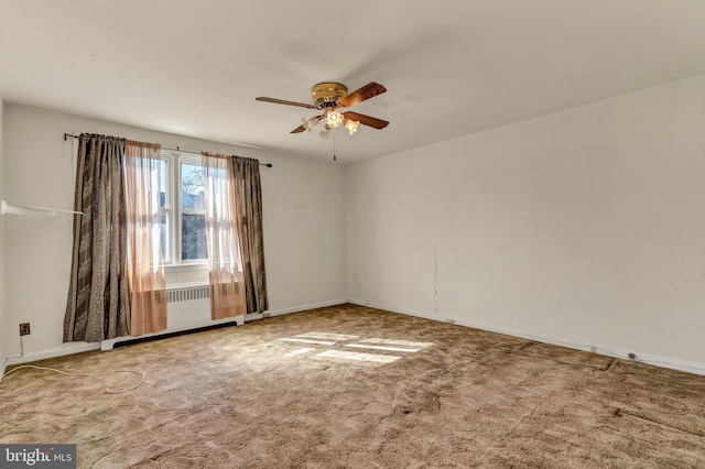 carpeted spare room featuring a ceiling fan and baseboards