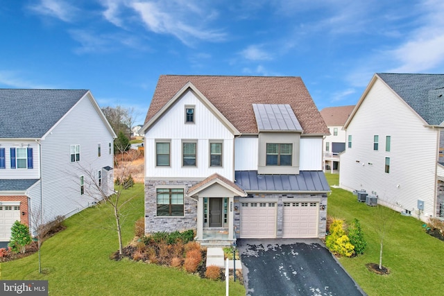 modern inspired farmhouse featuring a standing seam roof, stone siding, aphalt driveway, and a front yard