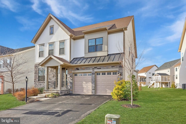 view of front of house featuring an attached garage, a front yard, a standing seam roof, stone siding, and driveway