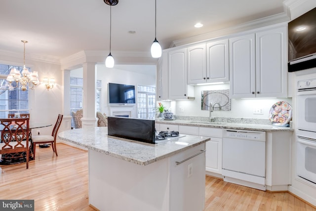 kitchen featuring white appliances, light wood-style flooring, crown molding, ornate columns, and a sink