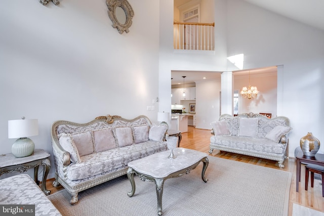 living room featuring light wood-type flooring, high vaulted ceiling, and a notable chandelier