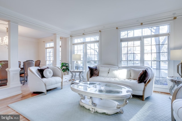 living area with plenty of natural light, decorative columns, and crown molding