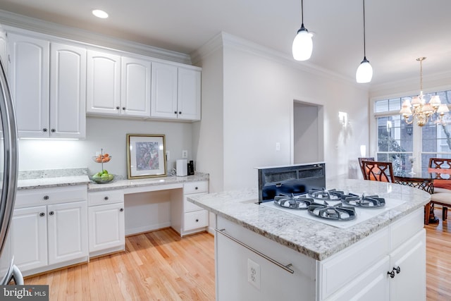 kitchen featuring light wood finished floors, a kitchen island, crown molding, white gas cooktop, and built in desk