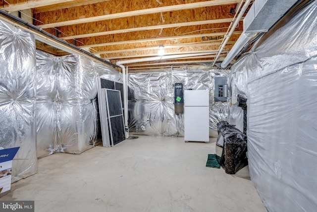 unfinished basement with freestanding refrigerator and electric panel