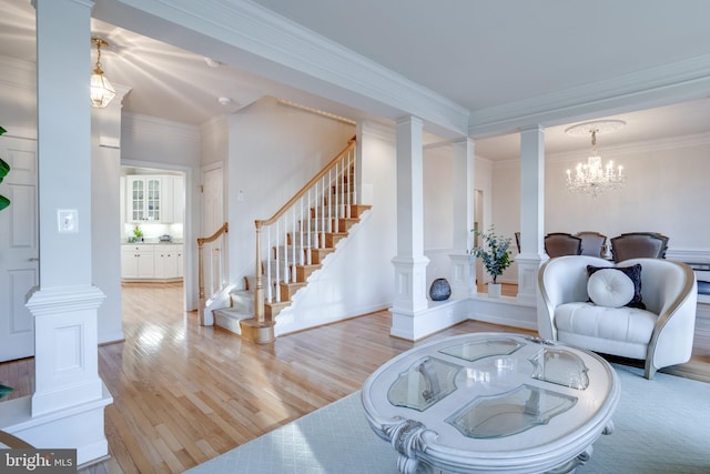 living room featuring decorative columns, stairs, crown molding, and wood finished floors