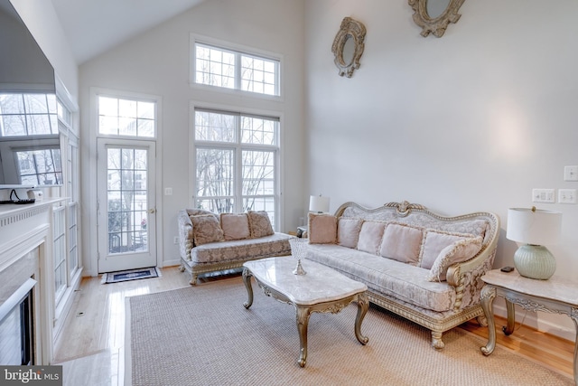 living area with a premium fireplace, high vaulted ceiling, and wood finished floors