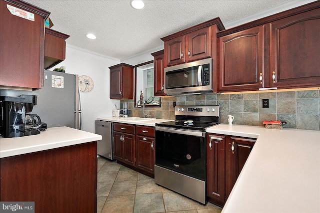 kitchen featuring tasteful backsplash, light countertops, appliances with stainless steel finishes, a sink, and a textured ceiling