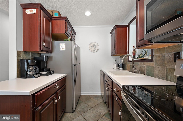 kitchen with a textured ceiling, light countertops, appliances with stainless steel finishes, and a sink