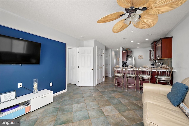 living area with a ceiling fan, recessed lighting, a textured ceiling, and baseboards