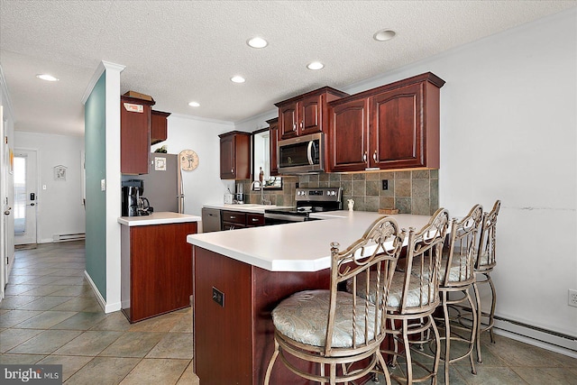 kitchen with a baseboard radiator, tasteful backsplash, appliances with stainless steel finishes, and light countertops