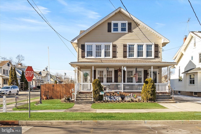 view of front of home with fence, a porch, and a front yard