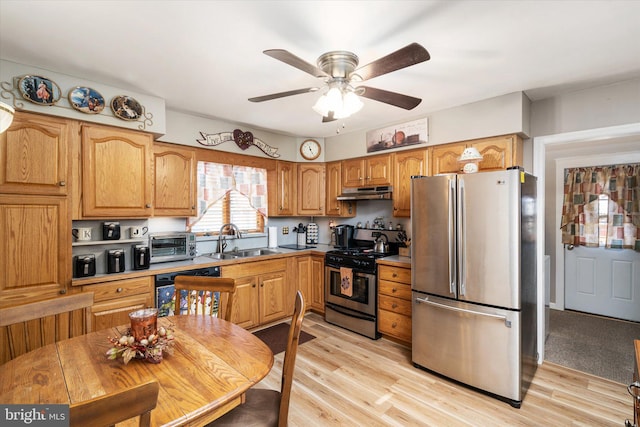 kitchen featuring a toaster, appliances with stainless steel finishes, a sink, light wood-type flooring, and under cabinet range hood