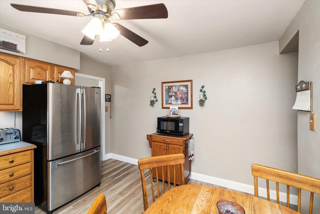 kitchen featuring baseboards, light wood-style flooring, freestanding refrigerator, light countertops, and black microwave