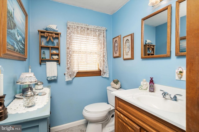 bathroom featuring baseboards, vanity, and toilet