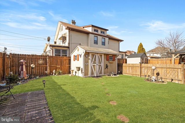 back of property featuring a storage shed, a lawn, a fenced backyard, a chimney, and an outdoor structure