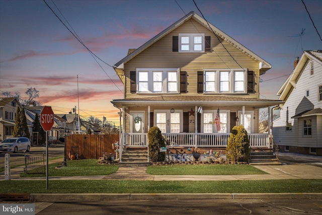 view of front of house with fence, a porch, and a front yard